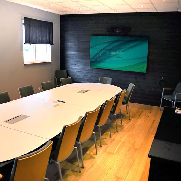 Konferensrum Revinge på Höllviksnäs med ovalt mötesbord, skärm och plats för mindre grupper