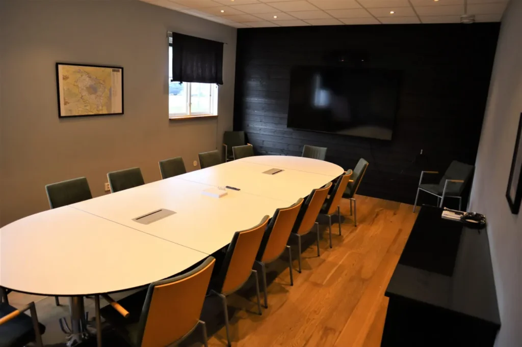 Konferensrum på Höllviksnäs med ovalt mötesbord, stor skärm och mindre gruppmöte