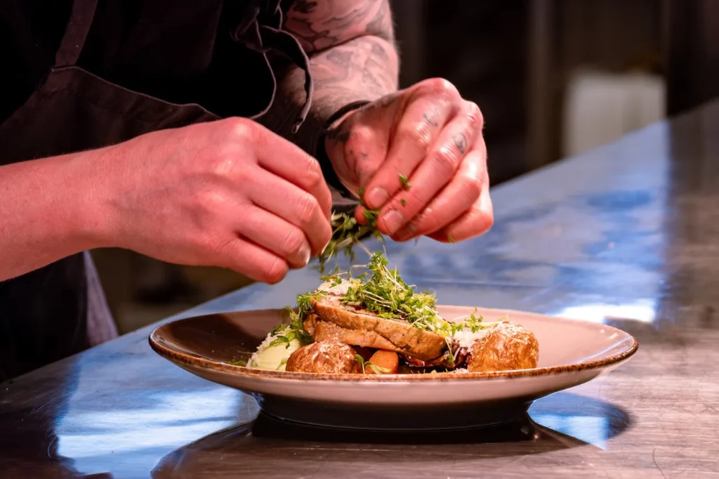 Matlagning på Höllviksnäs med uppläggning av varmrätt i restaurangköket